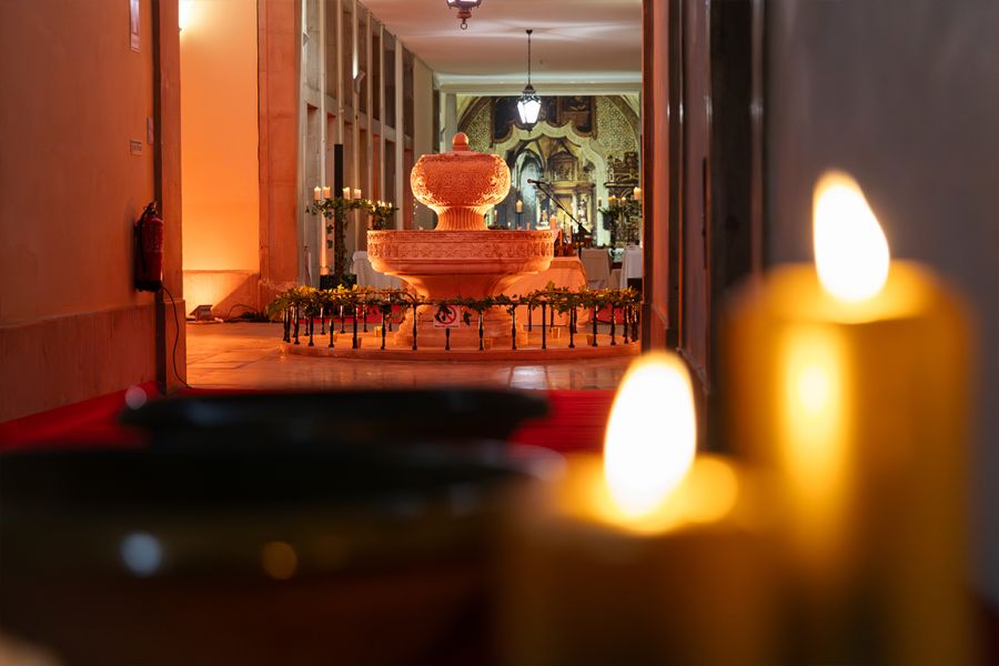 Corredor iluminado por velas, com uma fonte decorativa ao fundo