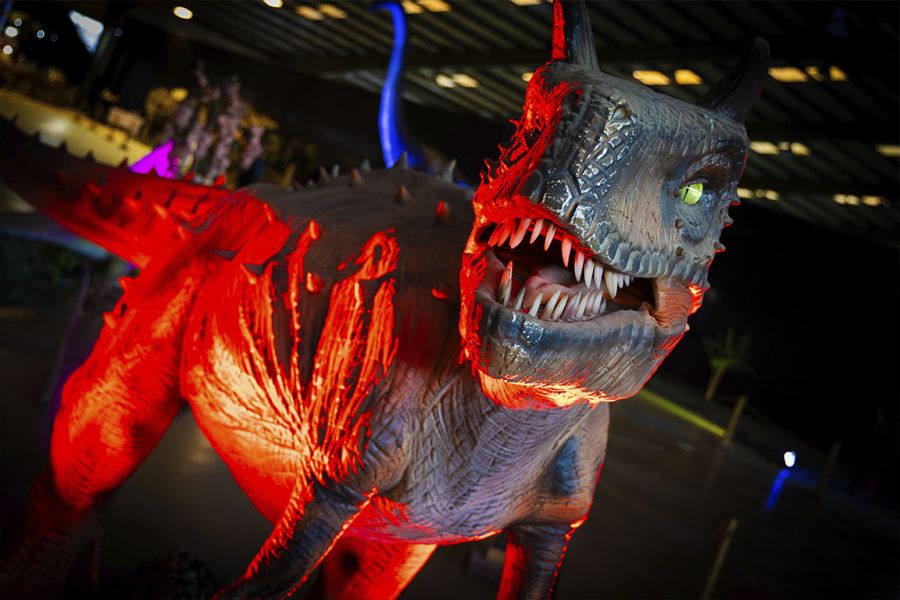 Dinossauro animado iluminado de vermelho numa exposição