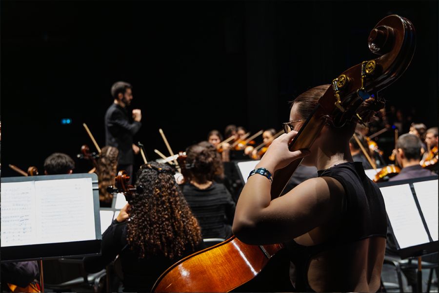 Violoncelista em primeiro plano durante um concerto de orquestra